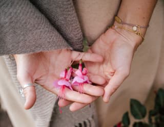 A young woman delicately holds pink fuchsia flowers in her hands