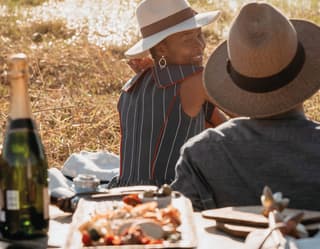 Smiling couple sitting on a blanket with a luxurious picnic spread and champagne