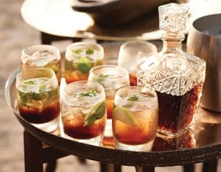 Silver tray topped with a crystal wine decanter and seven cocktails