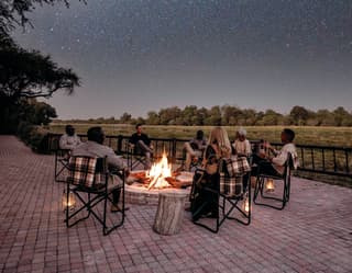 Friends and family sitting around a campfire under the milky way at night