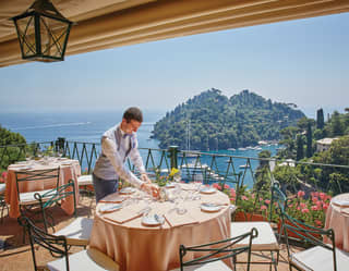 waiter setting the table at la terrazza with portofino harbour in the background