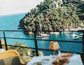 Soft-focus image of a dining table at Splendido Grill with views over the crystal Ligurian waters, where boats line the bay.