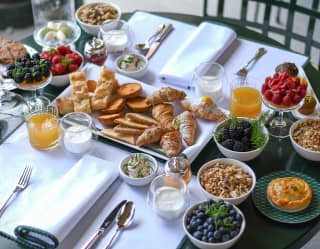 View over a breakfast table with pastries, fruit salad, a variety of berries, yoghurt and juice, served on Dav's terrace.