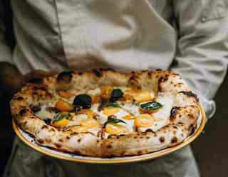 Close-up of a handmade freshly baked Italian pizza, topped with mozzarella, tomatoes and basil