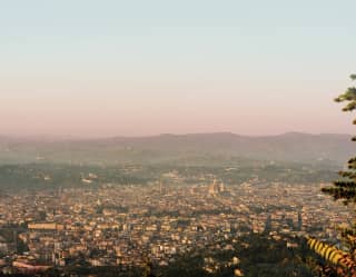 Florence spreads along the valley floor, walls pink in the late afternoon light. The Cathedral clearly visible above the roofline