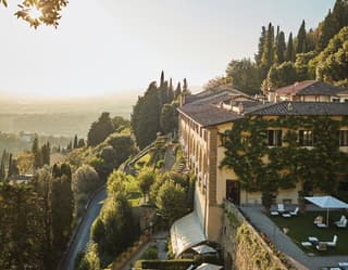 Yellow facade of a former hilltop convent coated with ivy and bougainvillea at sunset