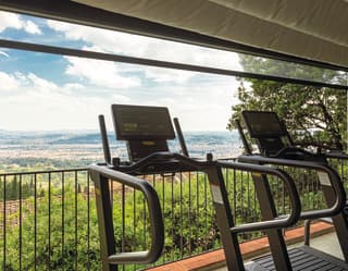 Two treadmills face the view of Florence spread out below, with an open glass wall offering up fresh breezes among the trees