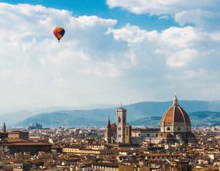 Brightly coloured hot air balloon over the city skyline of Florence and Il Duomo