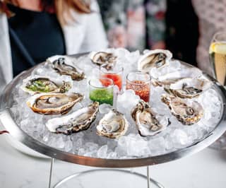 Close-up of oysters on a bed of ice in a circular sliver dish 