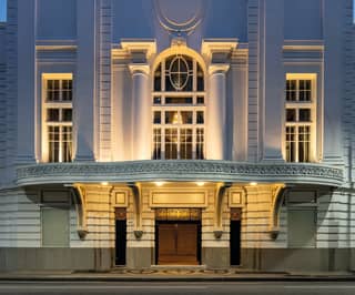 Art-deco exterior of a grand theatre illuminated by downlighting in the evening light