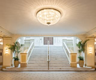 Spacious and light theatre foyer with a grand chandelier and marble steps 