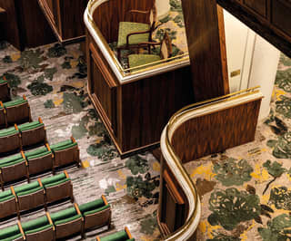 Birds eye view of an art-deco style theatre box with green accent chairs and flooring