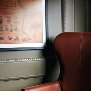 Close-up of a deep burgundy leather chair next to a sage-coloured wall panel