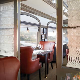 Two burgundy leather chairs at a dining car table next to a large window