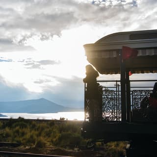 Dans un train, une femme sur une terrasse d'observation à ciel ouvert admire la vue