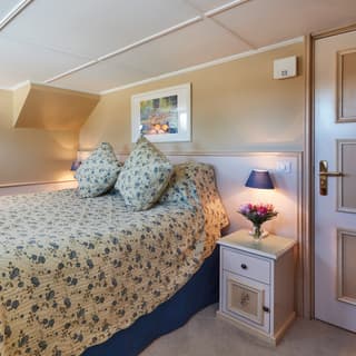 Vast pillowy bed with a blue and yellow floral bedspread in a bright lamplit cabin