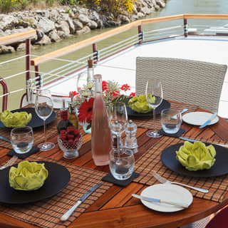 Wooden table on the top deck of a river barge set for lunch with green linen napkins