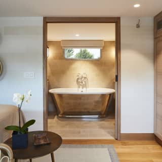 View through a door of a standalone copper rolltop bathtub from a stylish cabin