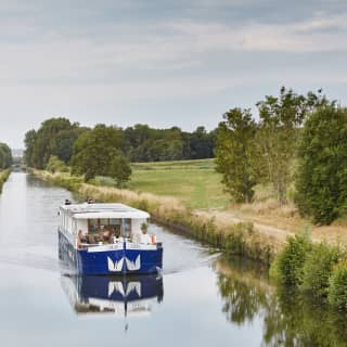 The white and blue Lilas barge cruises one of the peaceful waterways in France's Burgundy region, surrounded by nature.