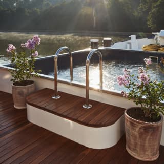 Sunrays sparkling on the surface of a plunge pool on the top deck of a luxury barge