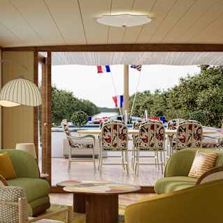 View through Marguerite's living area and open bifold doors to the deck and an outdoor table and chairs with floral cushions.