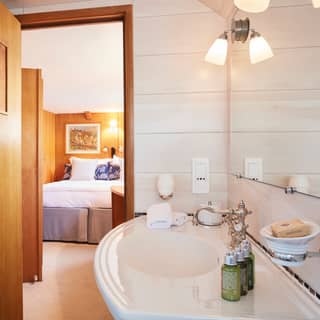Glamorous white-tiled cabin en-suite with a ceramic sink and green product bottles