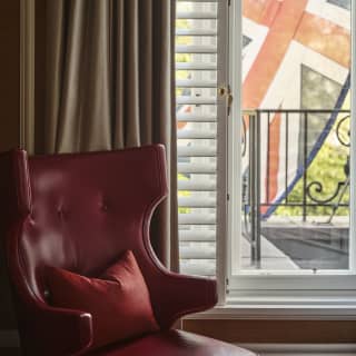 Close-up of a red leather Padrino club chair by the Oscar Suite window looking out on to a wall-mounted Union Jack flag.