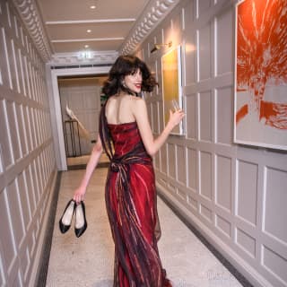 Lady in a red dress holding her heels and walking down a corridor