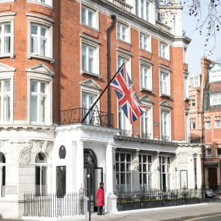 Doorman in a formal red coat standing at the entrance of The Cadogan in Chelsea