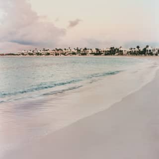 Low saturation image of Cap Juluca's beautiful, curved white beach, hemmed with luminous blue waters and pretty villas.