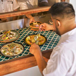 A chef places a bowl on the pass alongside three ready-to-serve plates as a waiter adds final touches, at Uchu restaurant.