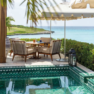 Close-up of a restaurant table beside an outdoor pool overlooking the Caribbean Sea