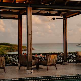 View across the pool feature on Uchu's terrace to a table for four beneath a canopied pergola with glorious ocean views.