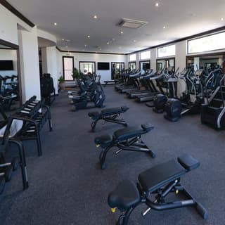 A spacious private gym is filled with treadmills, spin bikes, cross trainers, stairmaster, free weights and a bar bell station