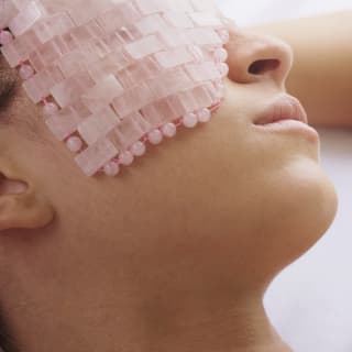 At the Cap Juluca Spa by Guerlain a female guest enjoys a facial treatment with a cooling rose quartz mask, seen in close-up.