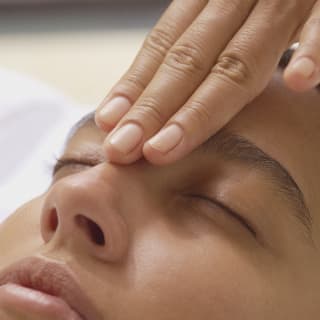 Close-up of the face of a female guest, with eyes closed, as she receives a gentle facial massage at the Cap Juluca Spa.