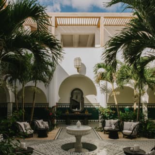 Enclosed in white archway walls, the Spa courtyard offers serenity with mosaic paths, mahogany chairs, palms and a fountain.