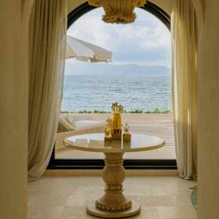 View into a room at the Spa by Guerlain where a marble table of products stands by an arched window with views to the ocean.
