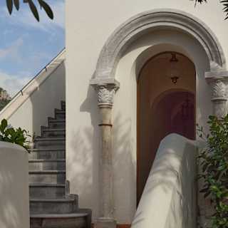 Detail of a terracotta walkway with arched door, with a walled external staircase leading to the roof terrace.