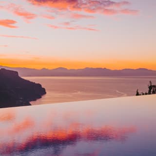 Reflections of fuchsia cotton candy clouds float effortlessly on an infinity pool as it fades into the purple horizon