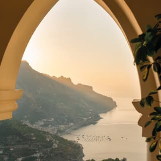 The setting sun turns the Lattari Mountain cliffs into silhouettes and the Naples yellow arch into deepest honey gold