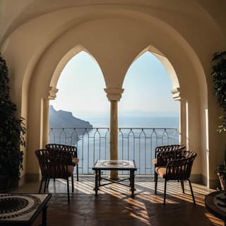 Coffee table in a shaded alcove with open arches framing the view of the Amalfi Coast