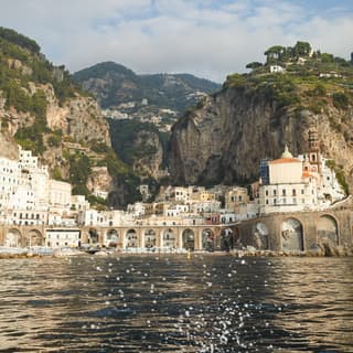 View from across the water of a coastal village nestled between tall cliffs