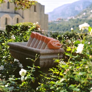 A stone trough containing folded orange and beige towels nestles into a bank of white dog roses in the hotel garden.