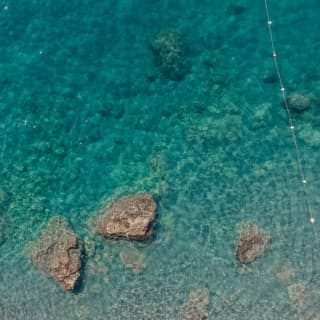 Birds-eye-view of craggy rocks surrounded by clear shallow water on an Italian coastline