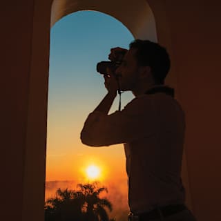 Close-up of a photographer's silhouette as he takes photos of the sunrise