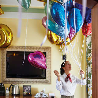 Waitress organising helium balloons in a yellow function room