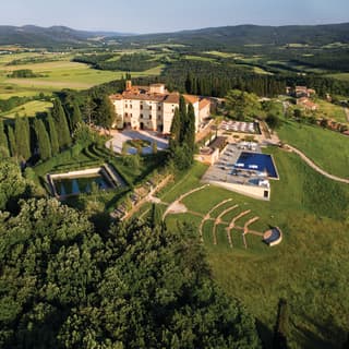 Aerial view of a sprawling castle with an outdoor pool and open-air amphitheatre