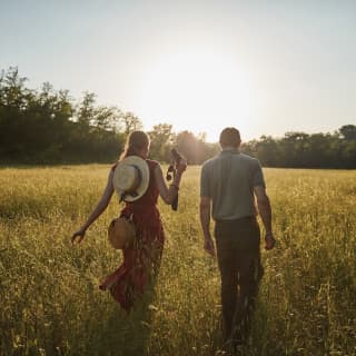 Un uomo e una donna con il binocolo che camminano nell'erba alta