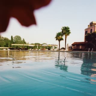 An Olympic sized outdoor pool stretches into the distance. On the far edge are two palms and the Hotel Cipriani’s pink walls